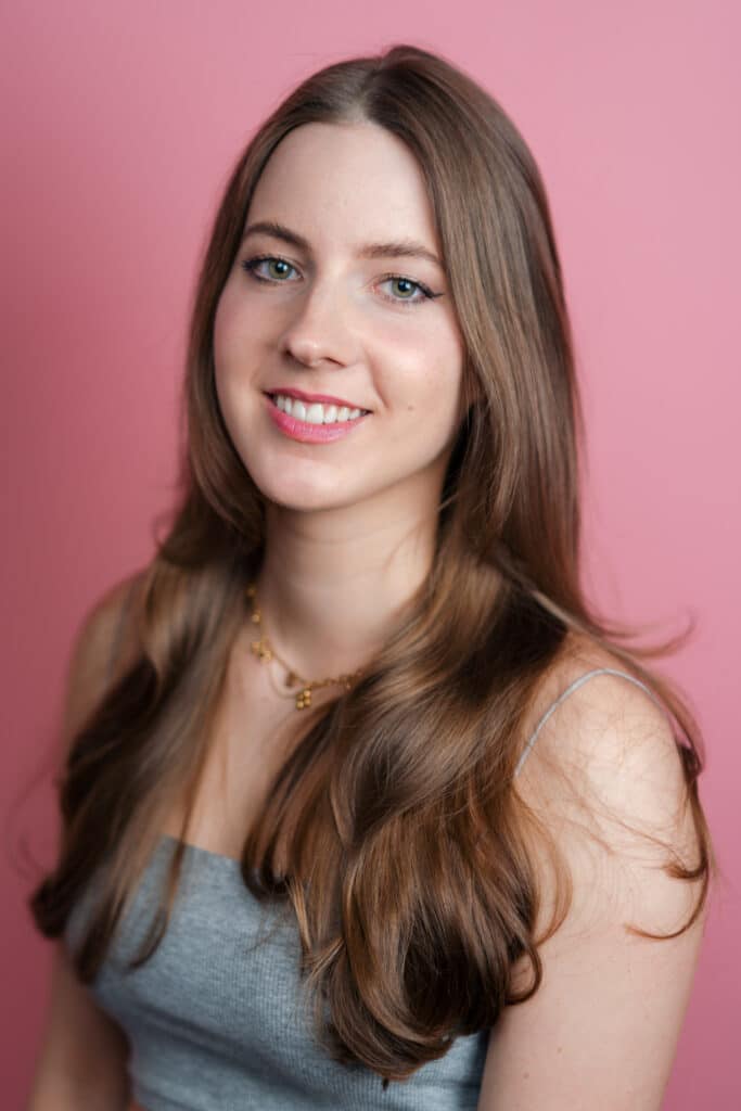 Portraitbild einer jungen Frau vor einem pinken Hintergrund. - Datingfotos