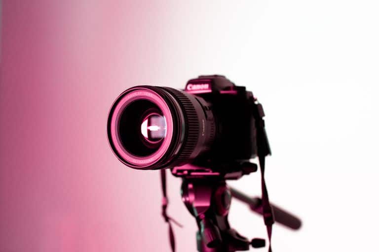Canon DSLR camera with lens on tripod in studio lighting, perfect for photography enthusiasts.