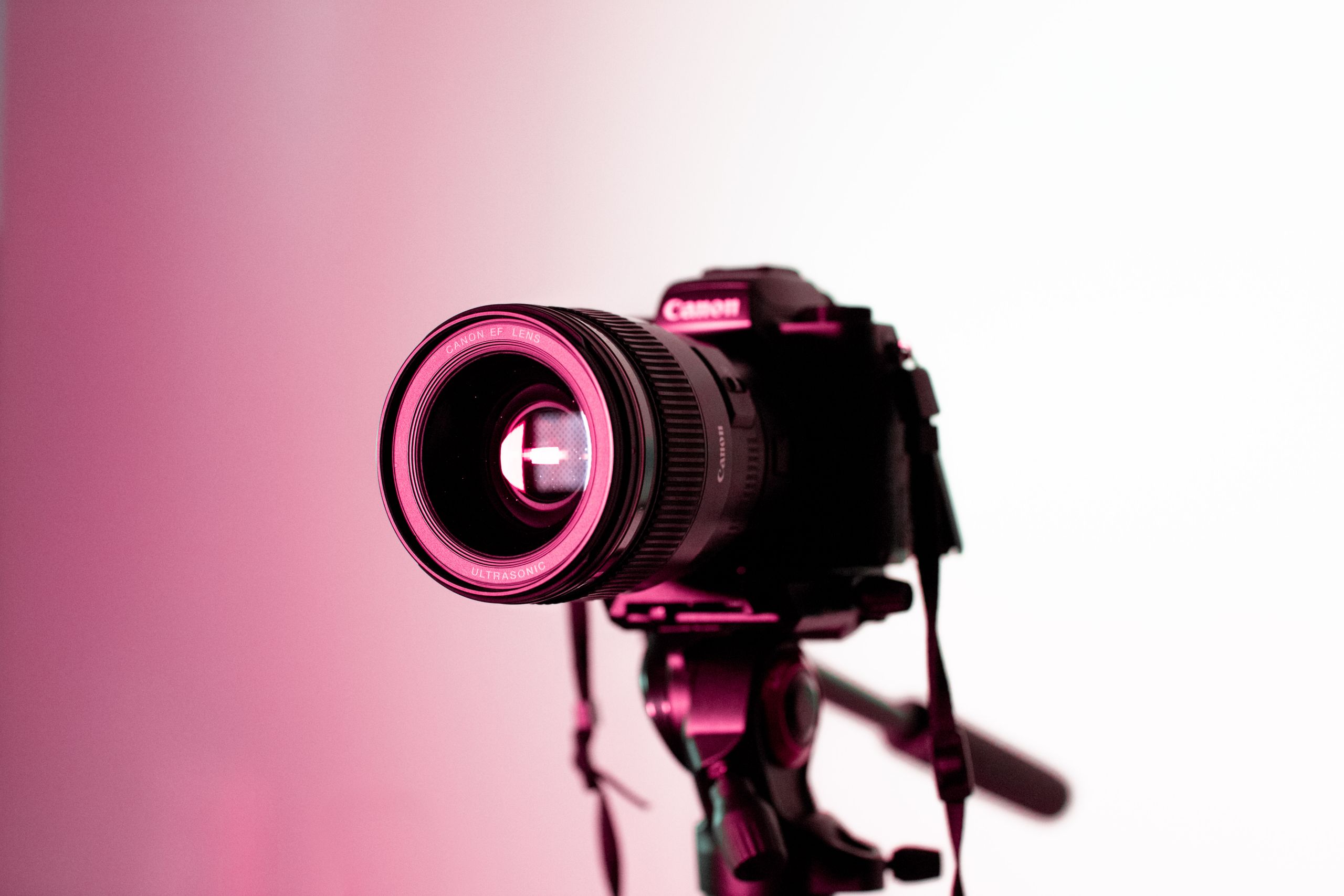 Canon DSLR camera with lens on tripod in studio lighting, perfect for photography enthusiasts.